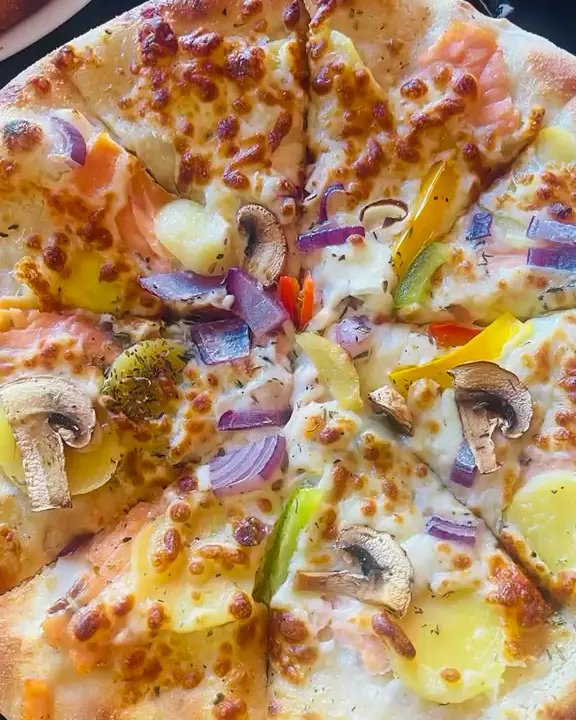 Pizza au saumon, pommes de terre, champignons, poivrons et oignons rouges
