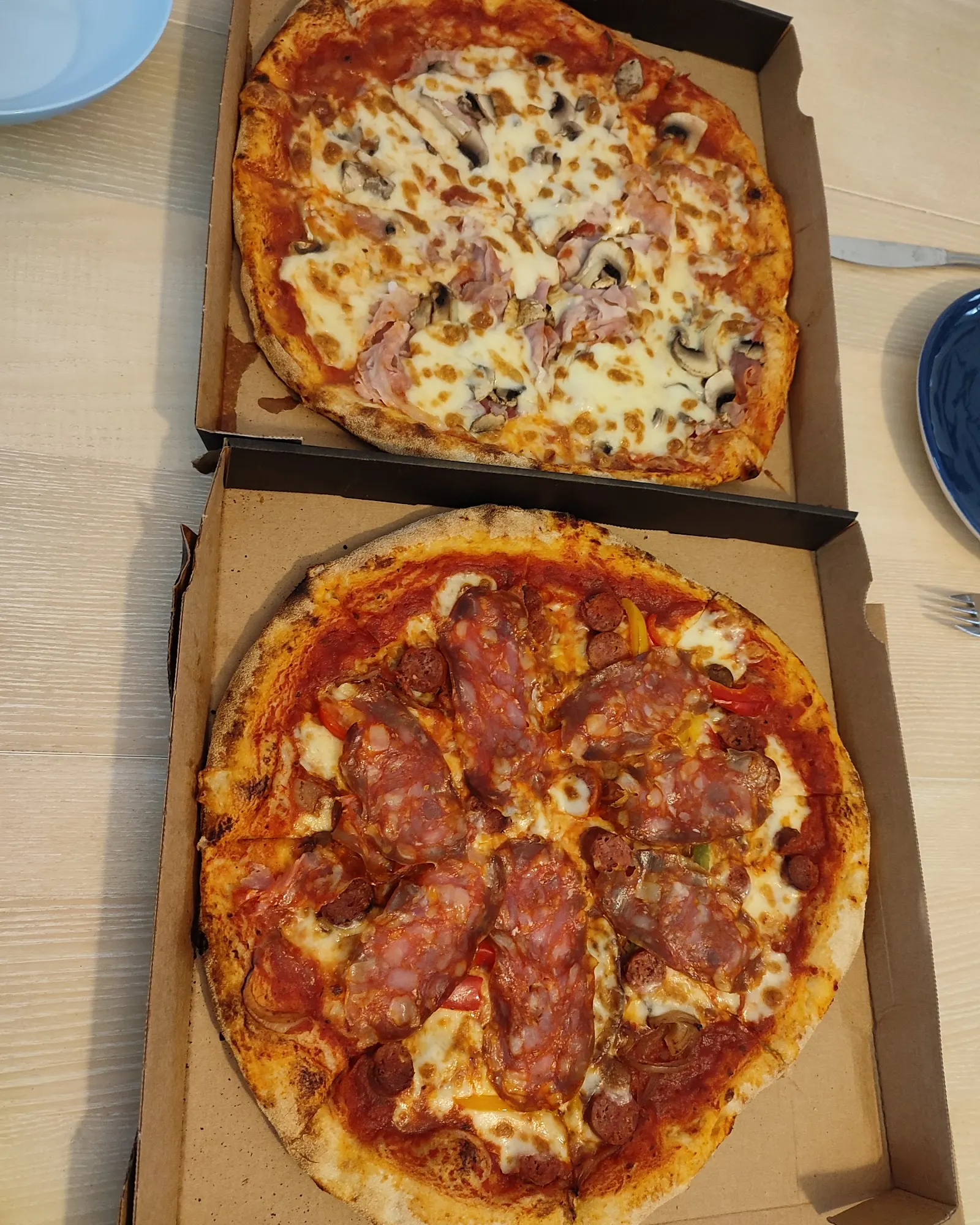 Deux pizzas à emporter dans leurs boîtes, jambon-champignons et charcuterie
